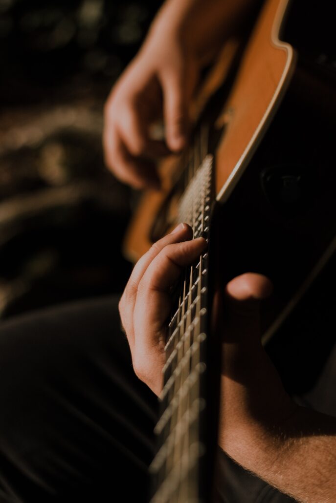 close up of person playing an acoustic guitar 